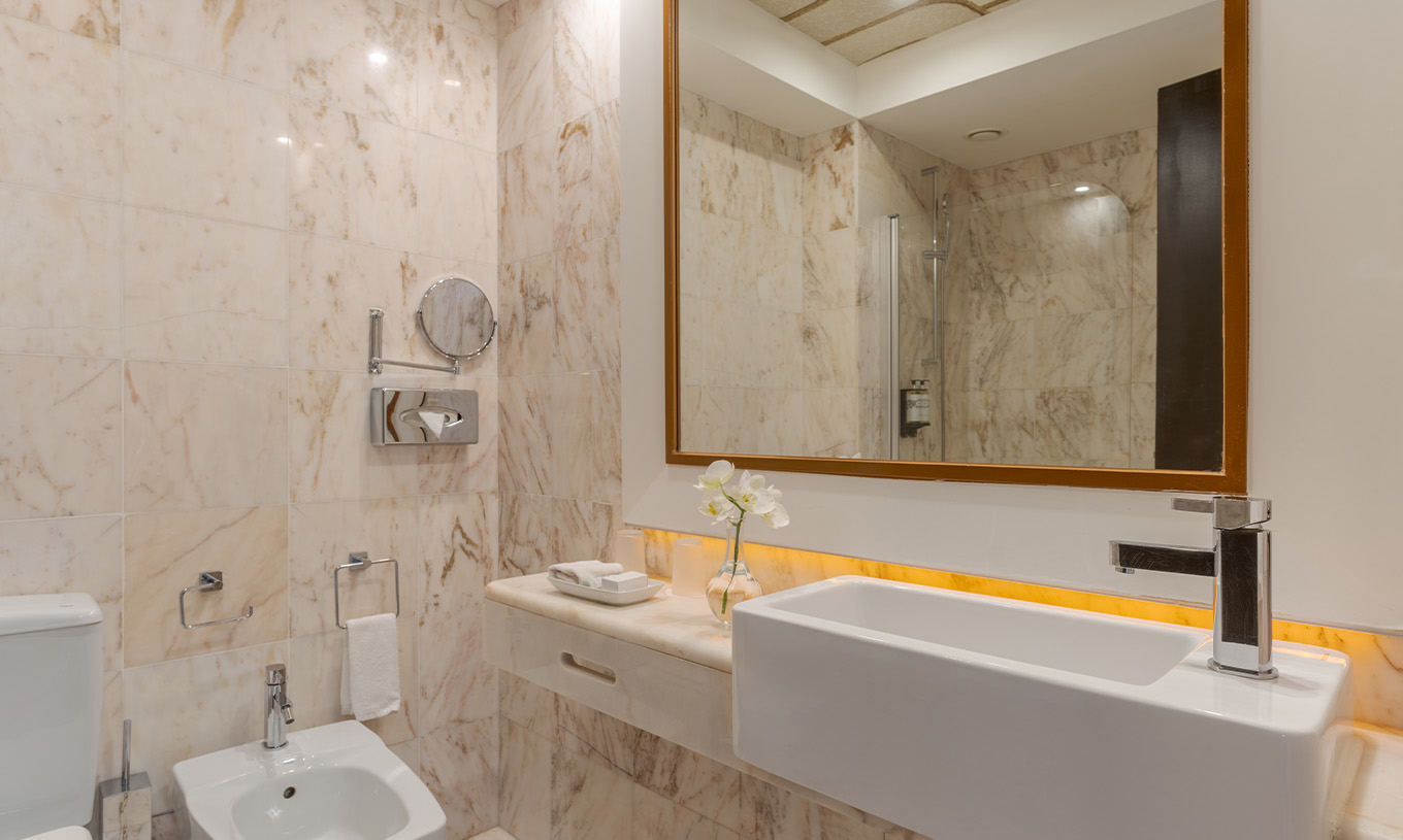 The Garden View Suite at Pestana Alvor Praia has a marble bathroom with bidet, sink, and flower vase