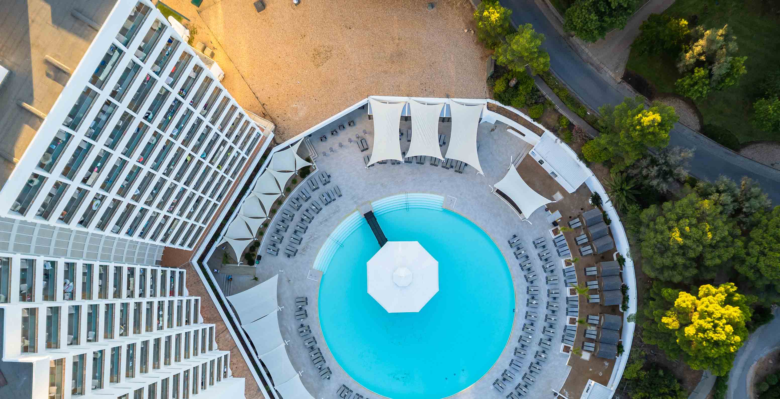 Aerial view of the Pestana Blue Alvor Beach pool, surrounded by sun loungers with parasols