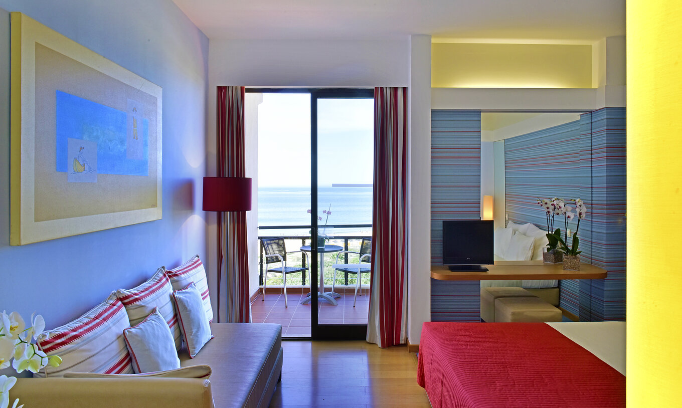 The Deluxe Sea View room at Pestana Dom João II includes a sofa and a balcony with tables and chairs overlooking the sea
