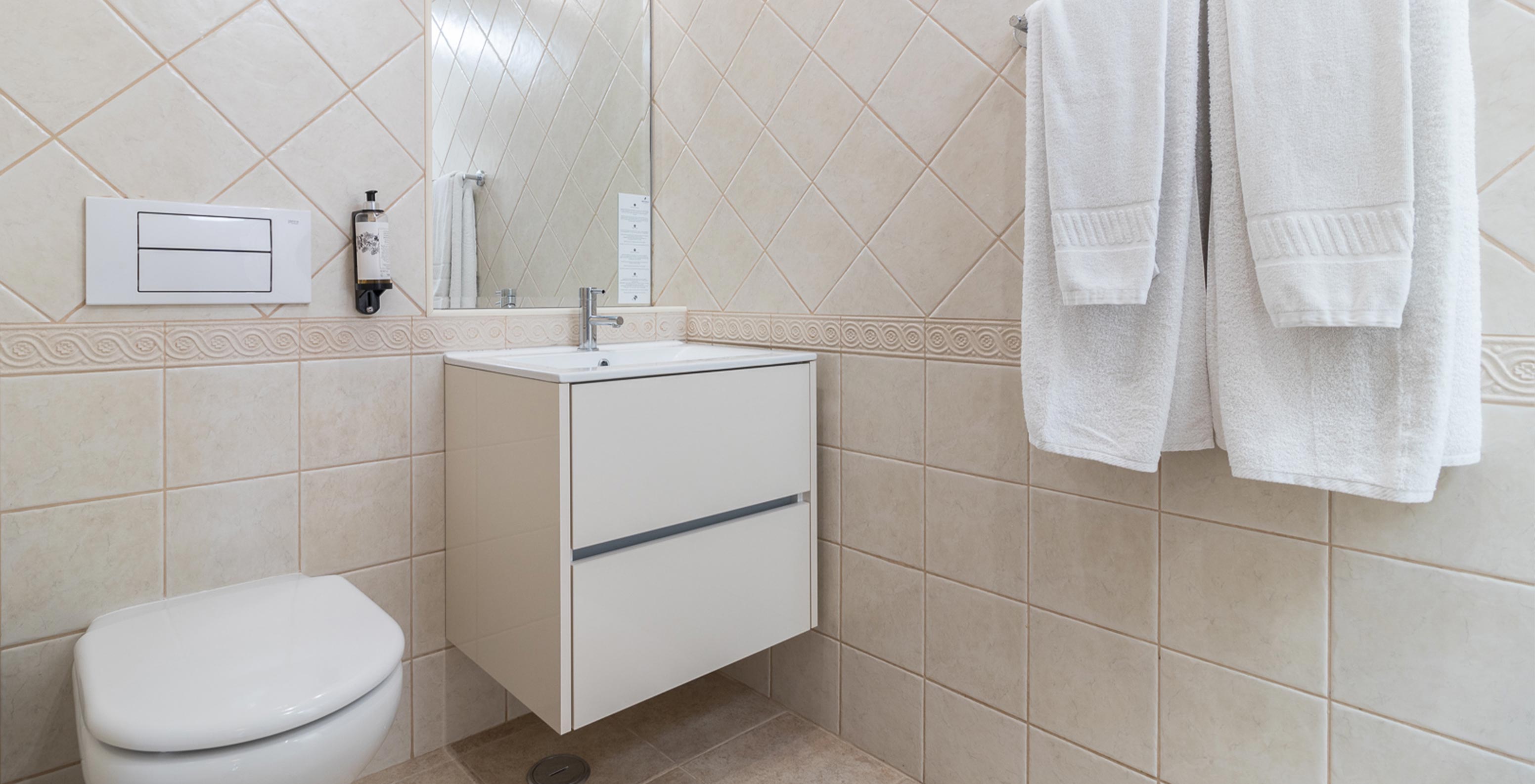 The two-bedroom apartment at Pestana Gramacho has an elegant bathroom with white towels and soft natural light