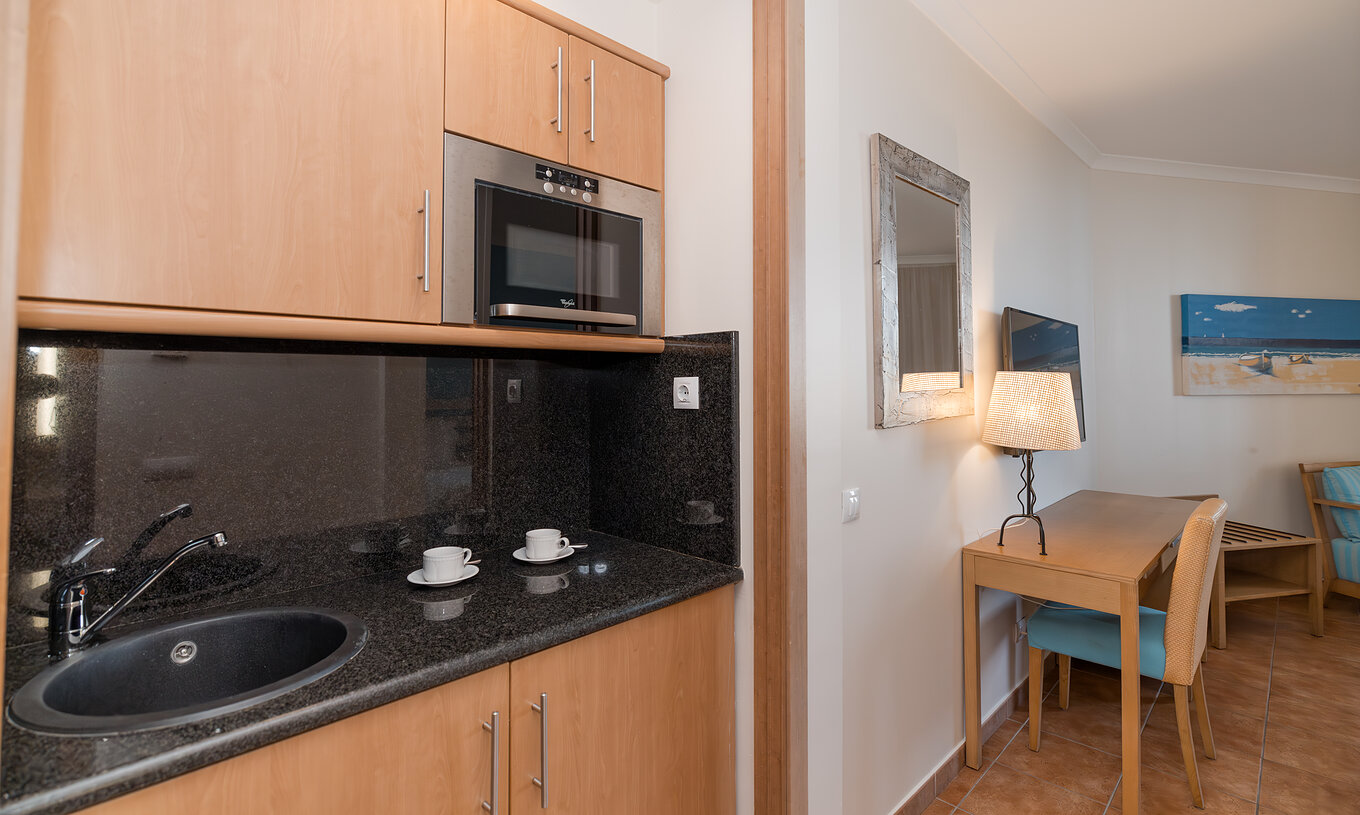 The Deluxe Garden View at Pestana Viking has a desk and a small kitchen with microwave and cabinets