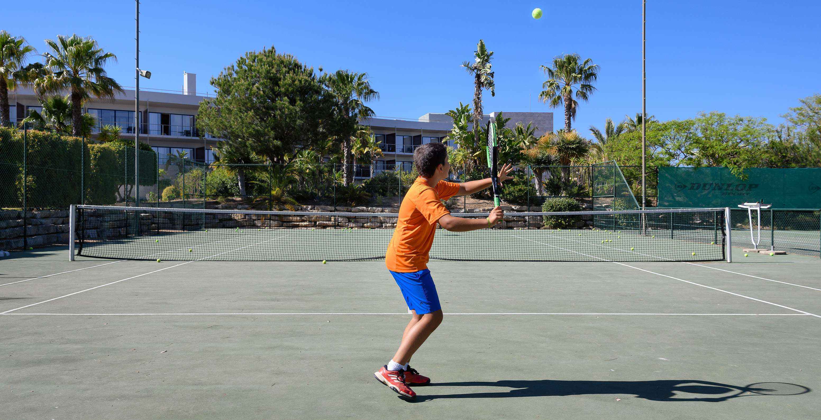 Child playing tennis on the tennis court at Pestana Vila Sol - Vilamoura, Hotel with Golf and Spa