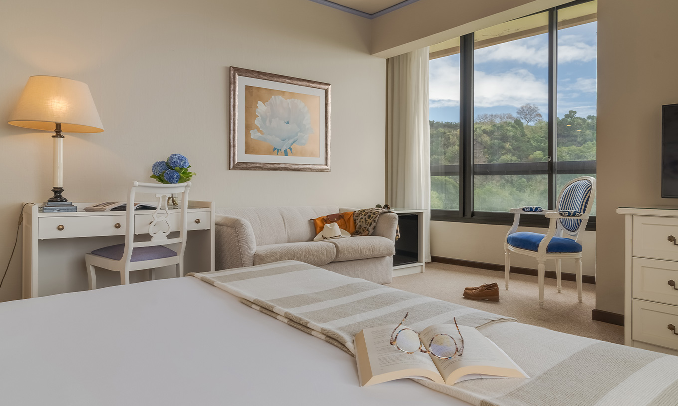 Standard Sea View room at Pestana Bahia Praia has a desk, a sofa and a chair near the window, with garden view