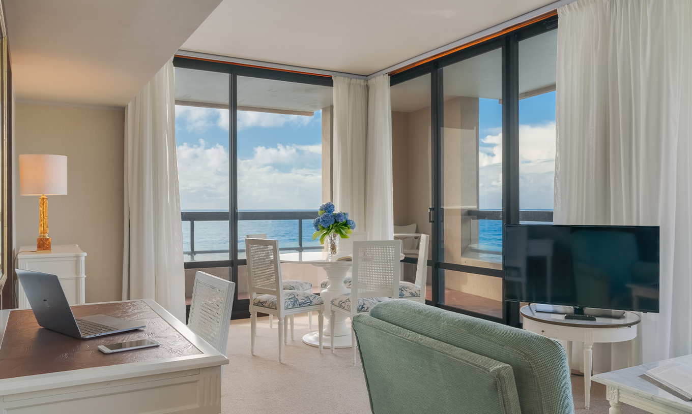 Suite at Pestana Bahia Praia has a living room with desk, table and sofa with TV, with a view of the sea