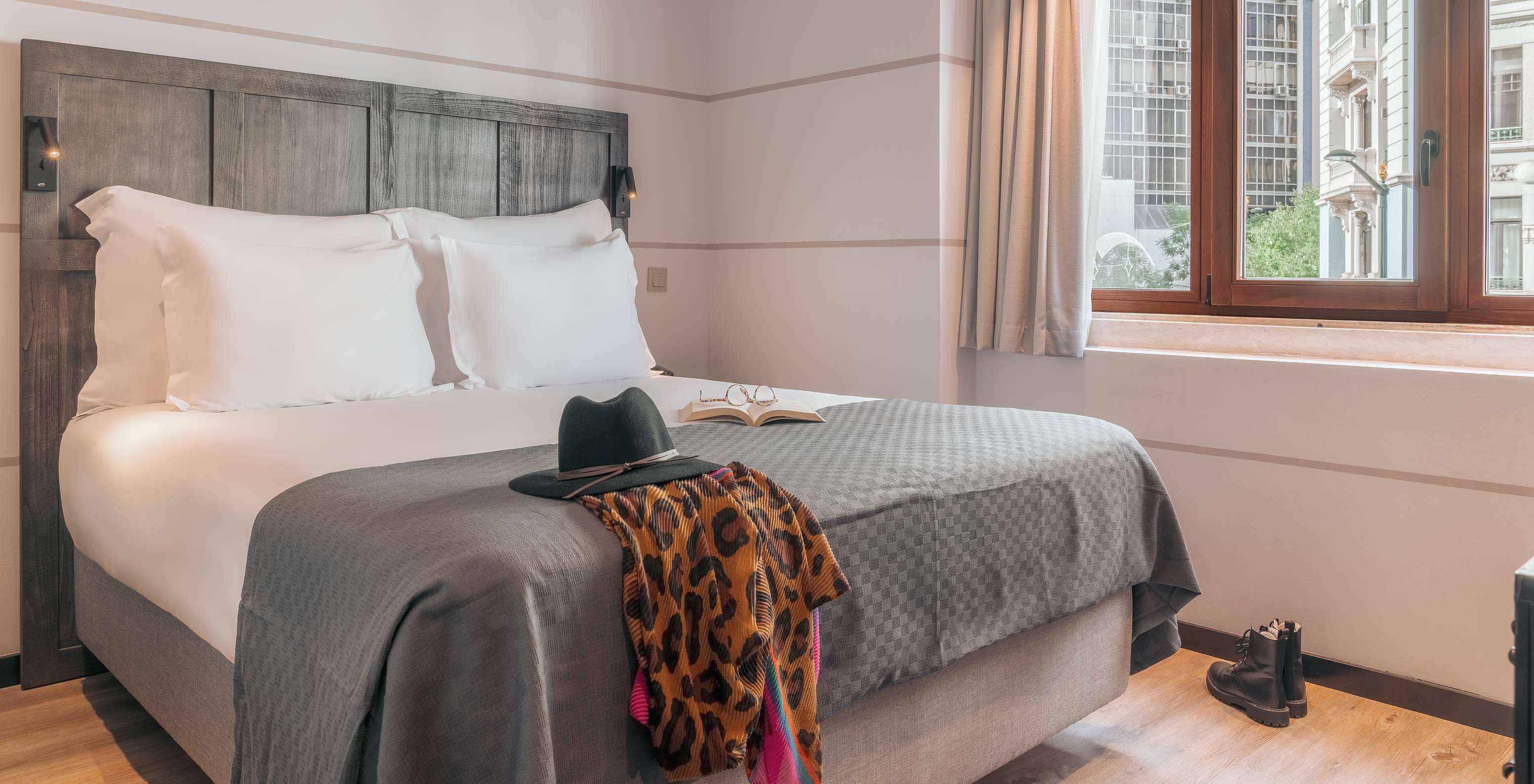The Vintage Room at Pestana Lisboa Vintage has a double bed with headboard and gray blanket, boots on wooden floor