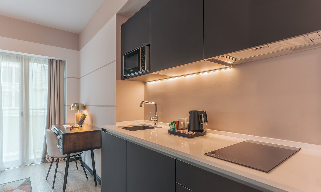 The Junior Suite at Pestana Lisboa Vintage has a kitchen unit with stove, microwave and a desk with chair