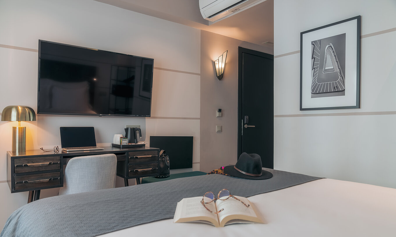 The Vintage Room at Pestana Lisboa Vintage has a double bed with gray blanket, a desk with computer and TV