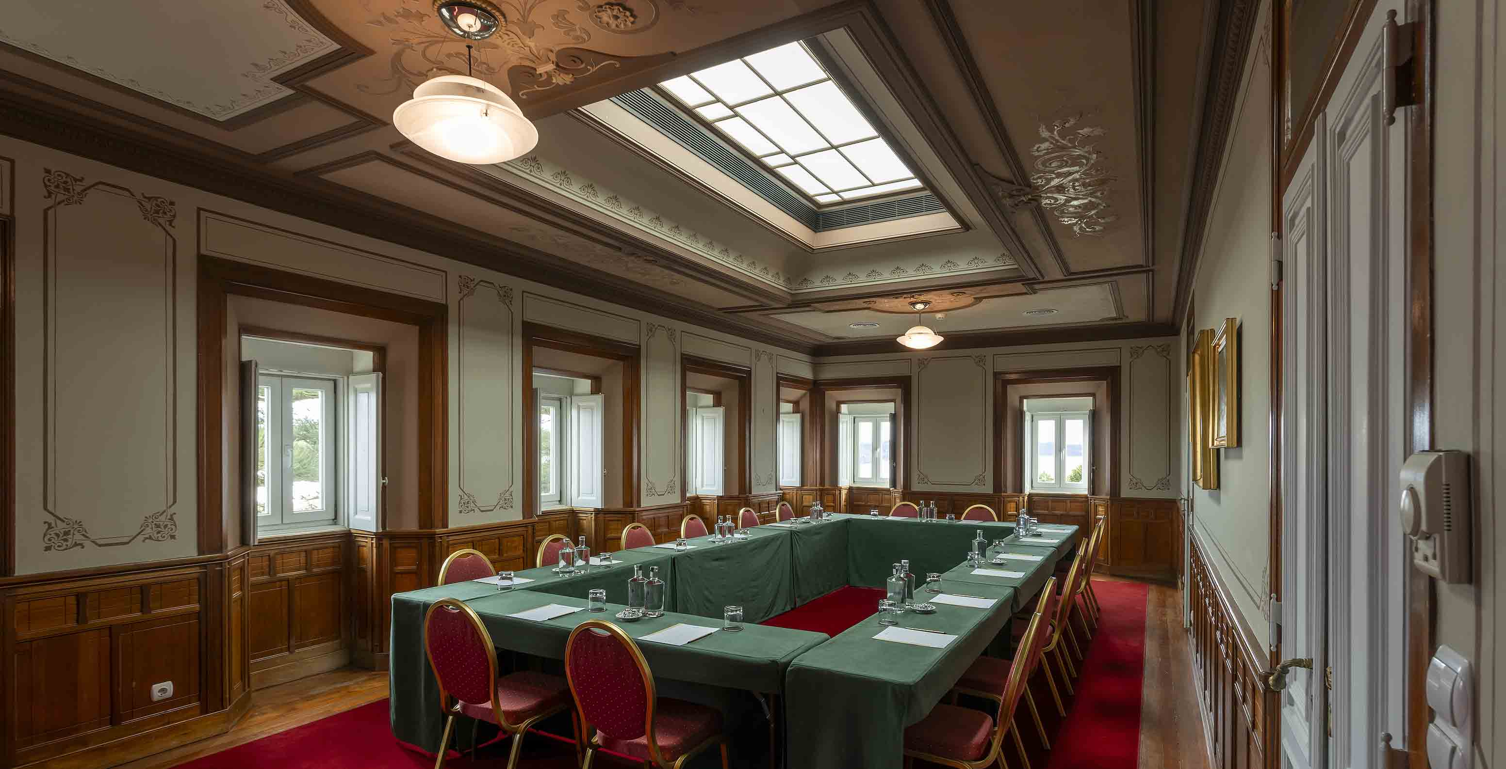 Pestana Palace Lisboa has a meeting room with a rectangular table, surrounded by windows, including a ceiling window