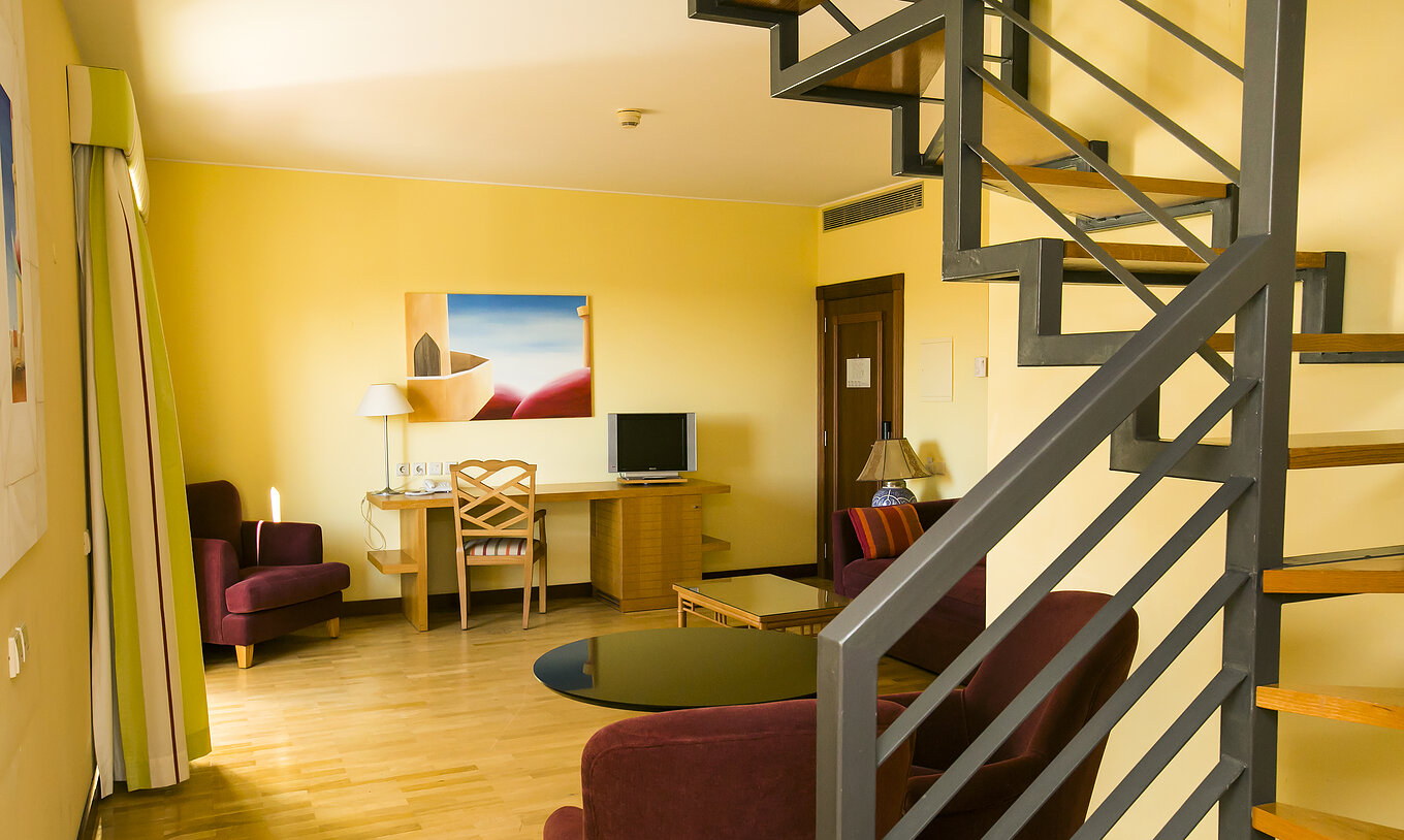 The Deluxe Mezzanine Suite of Pestana Sintra Golf has a room with sofa, armchairs, television, and a picture on the wall