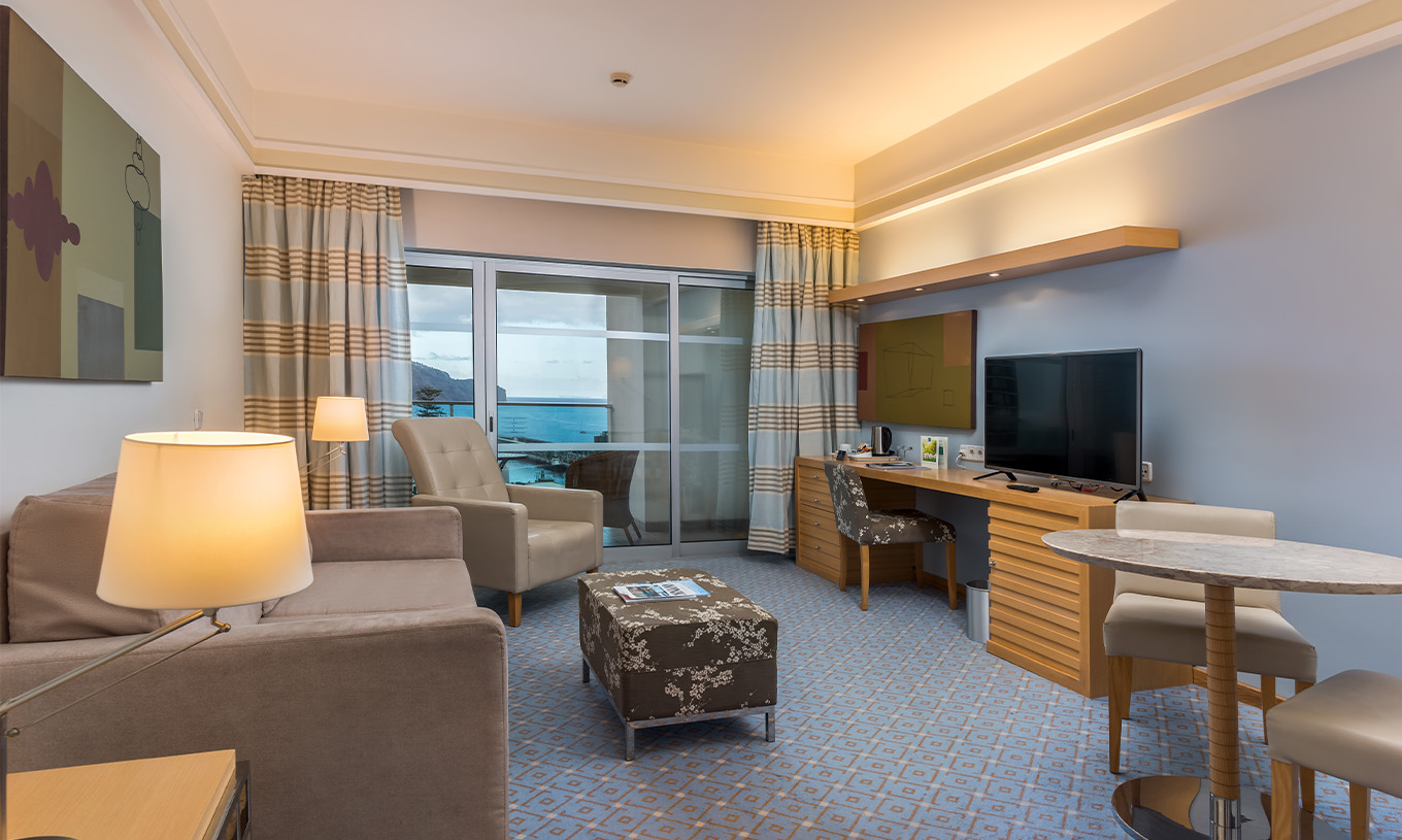 The Superior Classic Double Room with Sea View at Pestana Carlton Madeira has a seating area with a sofa, TV, and balcony