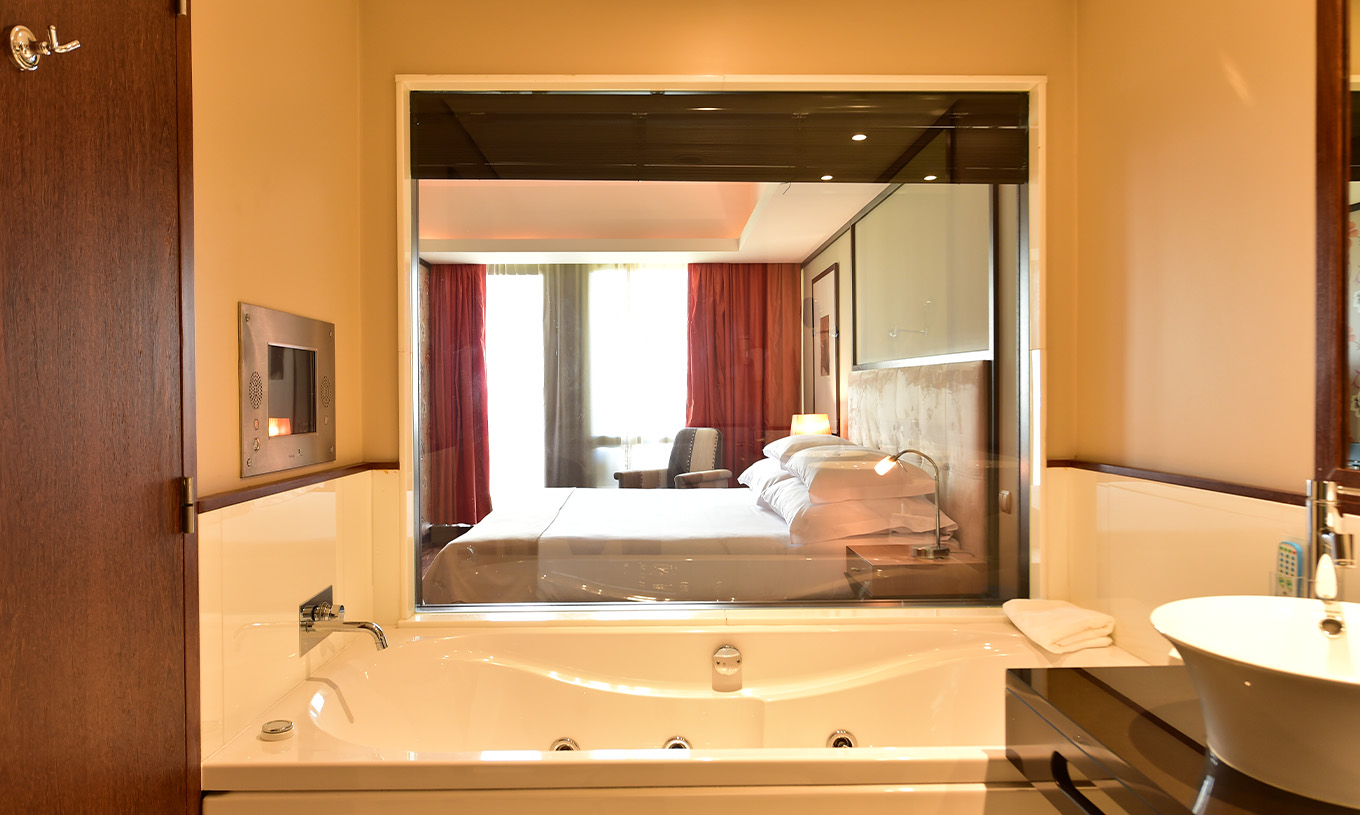 The Presidential Suite at Pestana Casino Park has a bathroom with a bathtub overlooking the double bed in the room