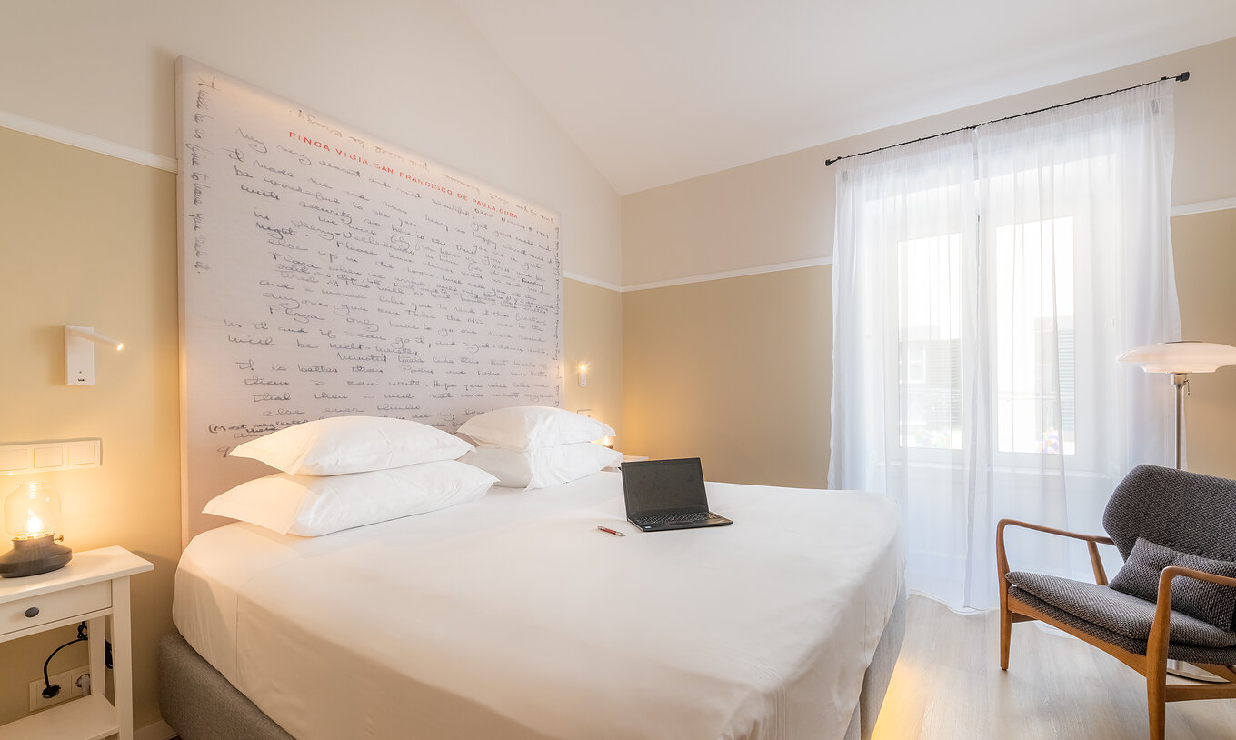 The Cozy room at Pestana Fisherman Village includes a double bed with a headboard with written phrases and an armchair