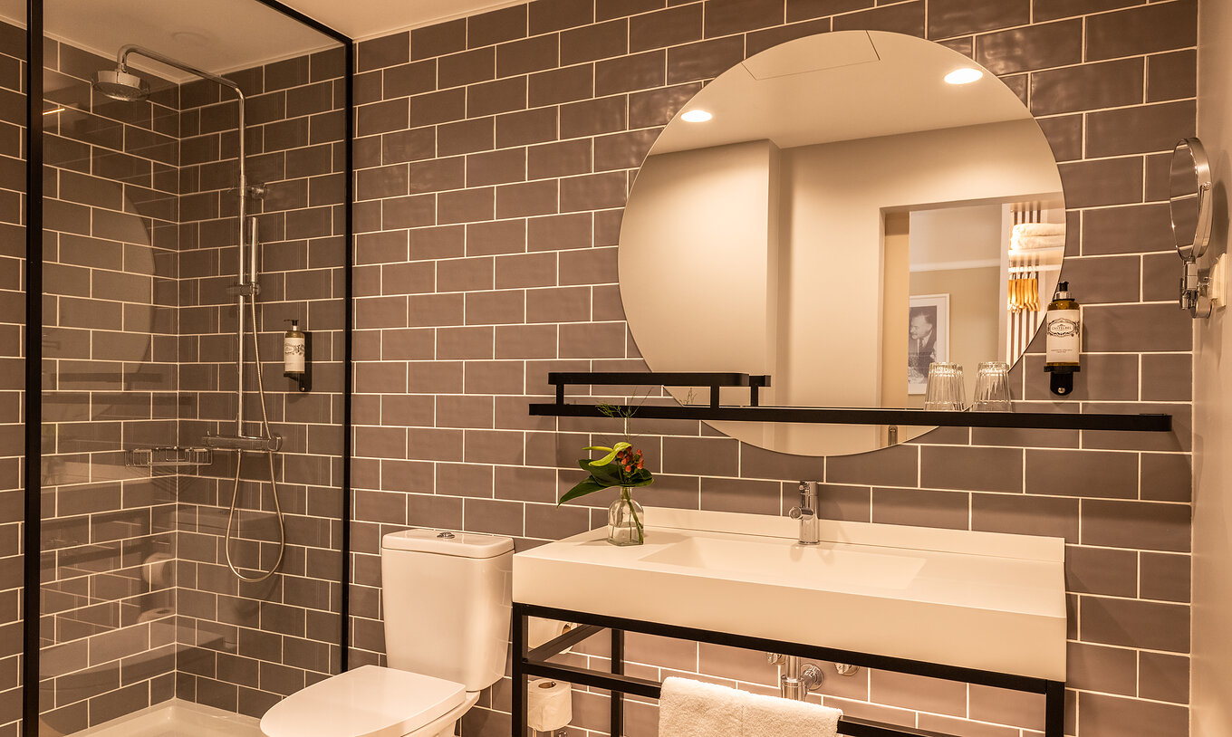 The Superior Room at Pestana Fisherman Village has a bathroom with a shower with black details and a round mirror