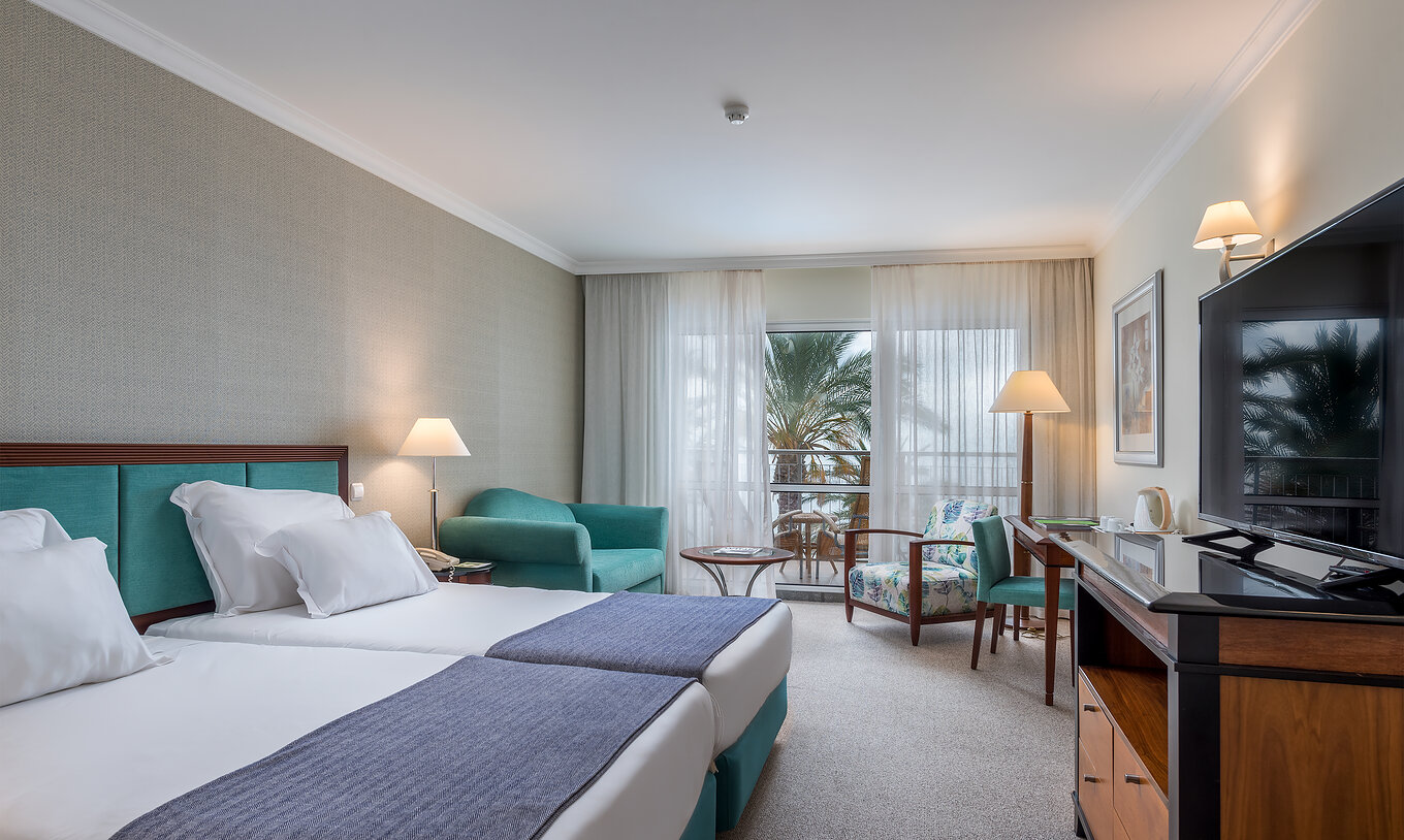 The Classic Inland View Room at Pestana Grand has two single beds, TV and an armchair