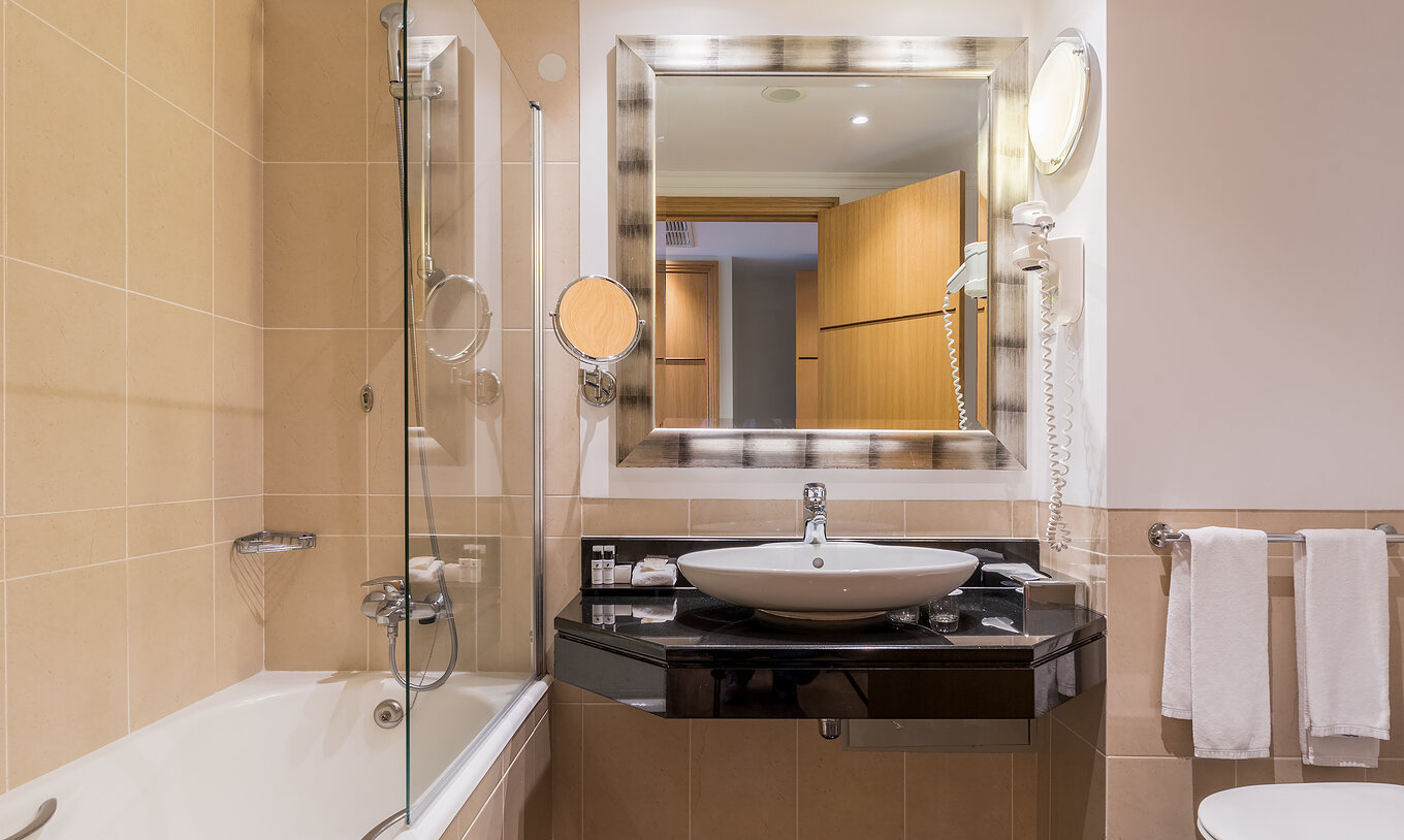 The Classic Sea View Room at Pestana Grand has a bathroom with sink, bathtub with shower and towel