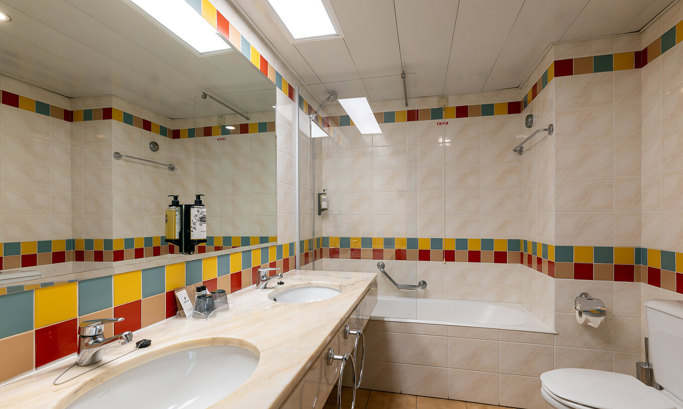 The Pestana Ocean Bay All Inclusive Junior Suite Sea View has a tiled bathroom with a bathtub and two washbasins