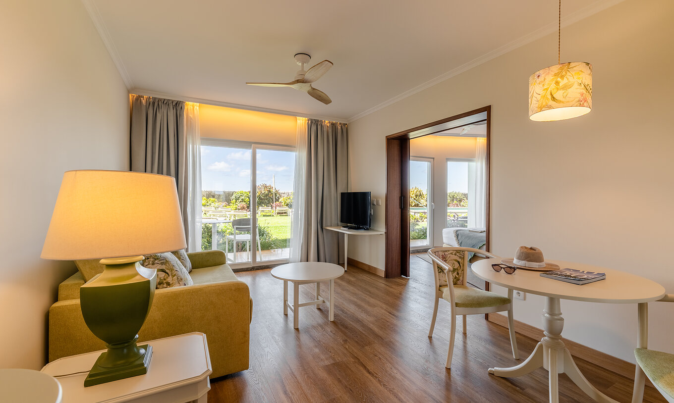The Pestana Ocean Bay All Inclusive Junior Suite Sea View has a bright living room with a sofa, a coffee table, and a dining table