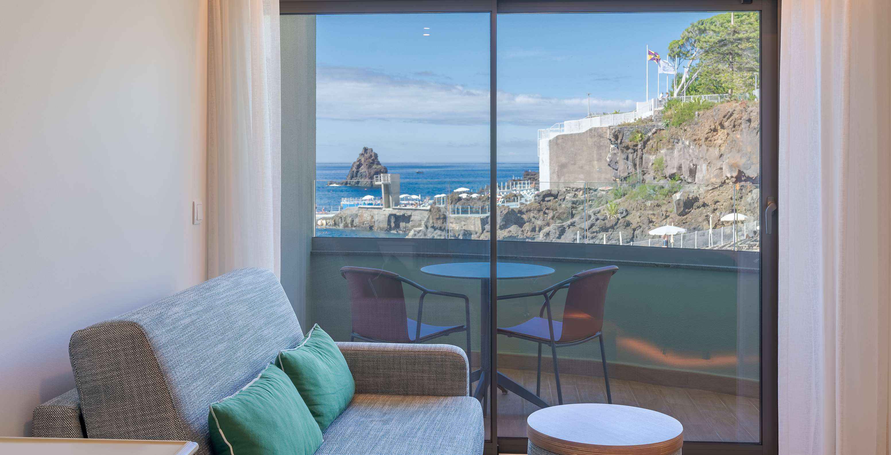 The Classic Lateral Sea View room at Pestana Vila Lido Madeira features a sofa next to the balcony with lateral sea view