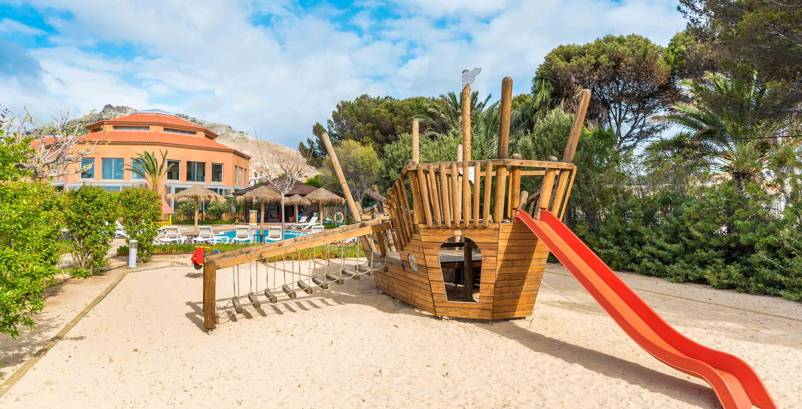 Pestana Porto Santo playground with big wooden boat, red slide under blue sky