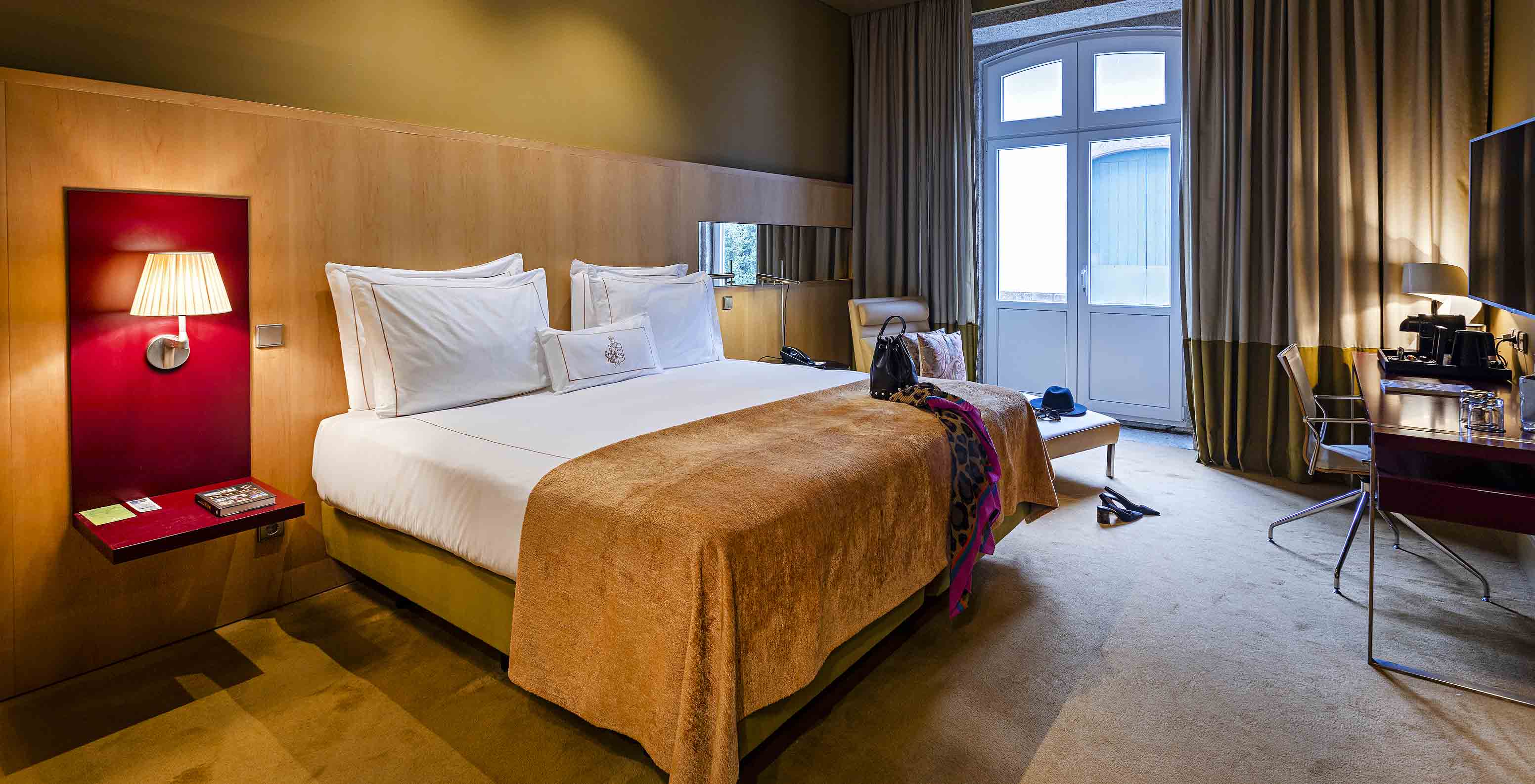 Pestana Palácio do Freixo’s Classic room has a large window, double bed, and a bedside table