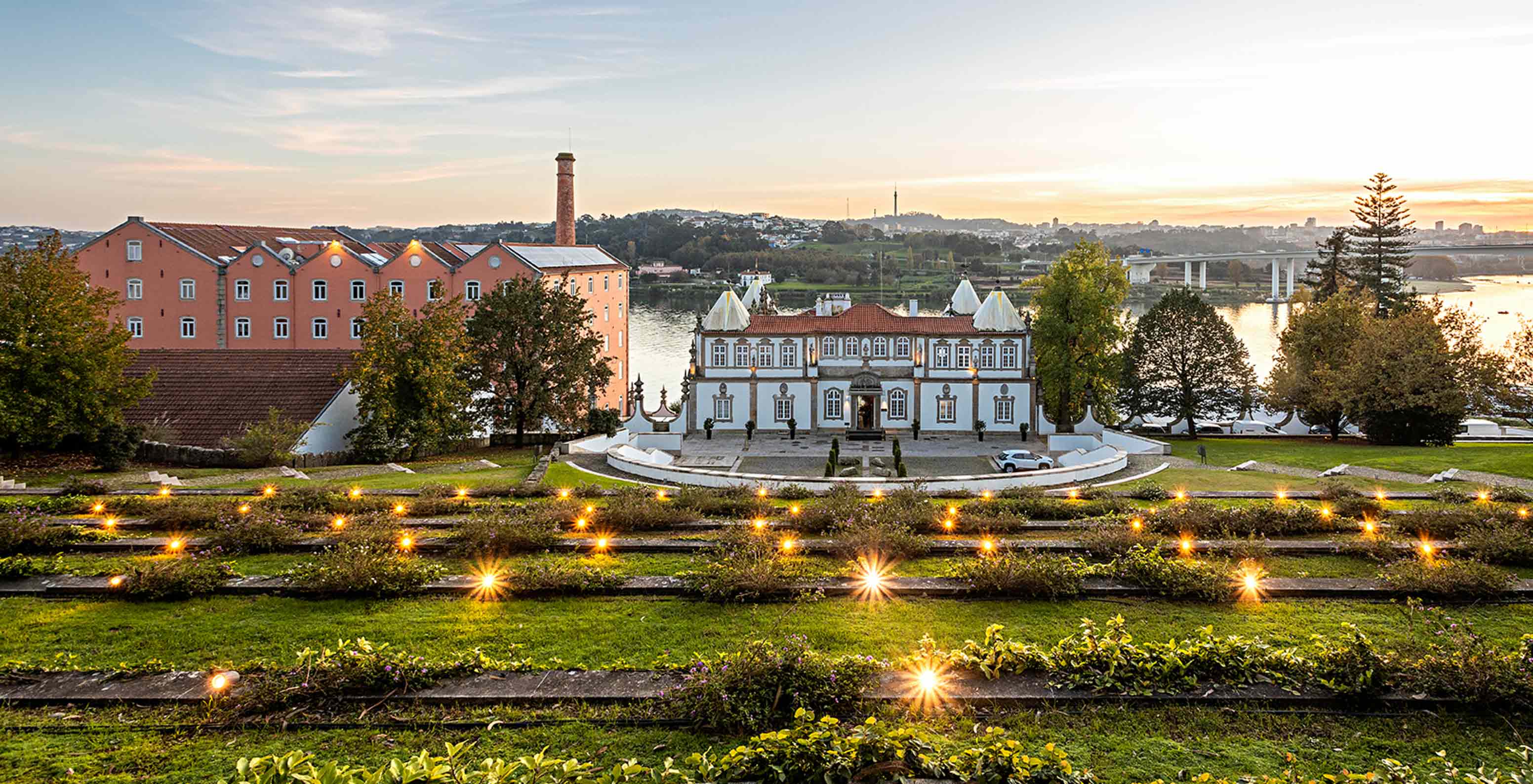 Exterior view of the façade of Pestana Palácio do Freixo surrounded by gardens overlooking the Douro River at sunset