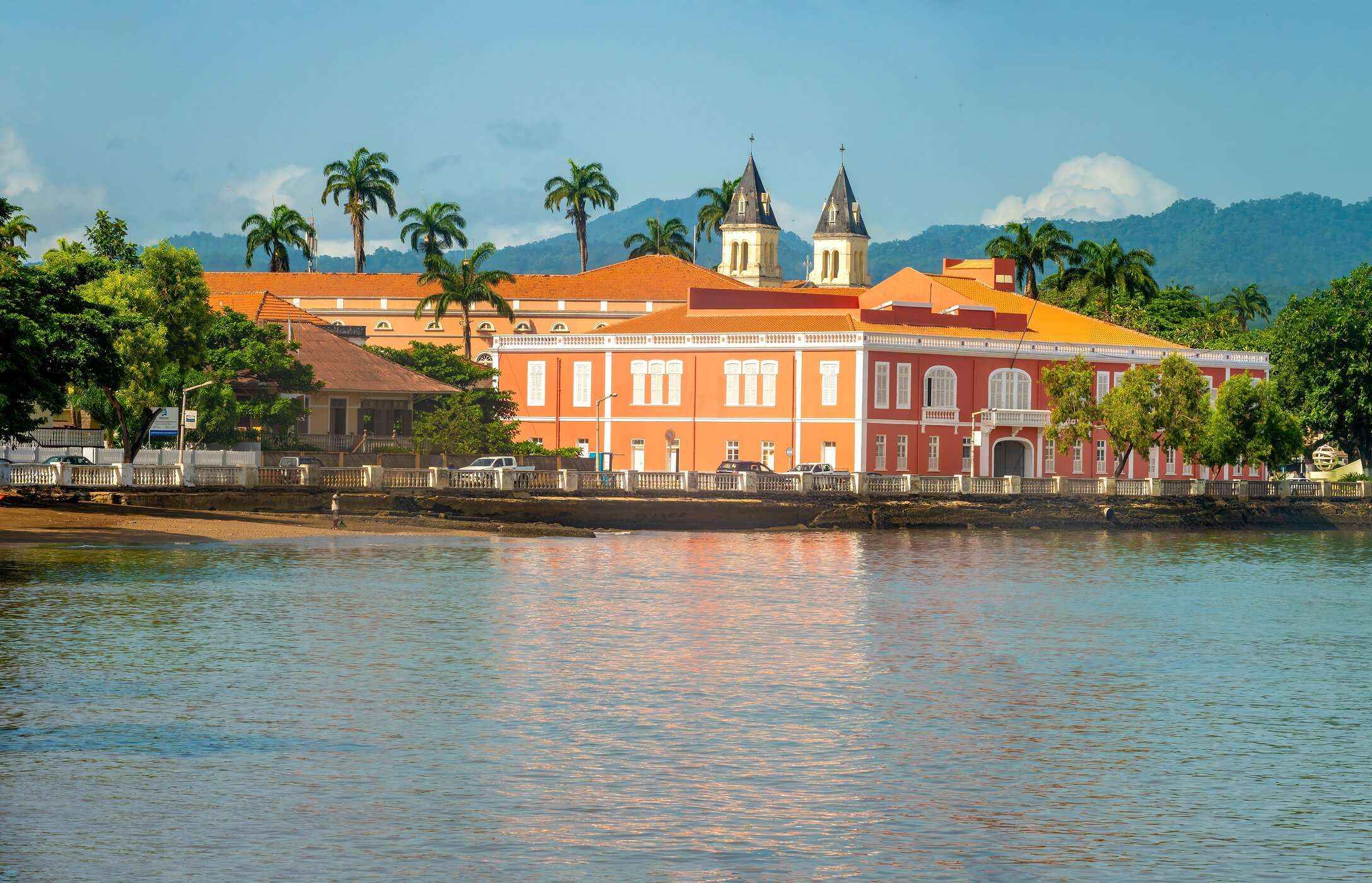 Panoramic view of a historic building in São Tomé and Príncipe with orange facades, located in front of the sea.