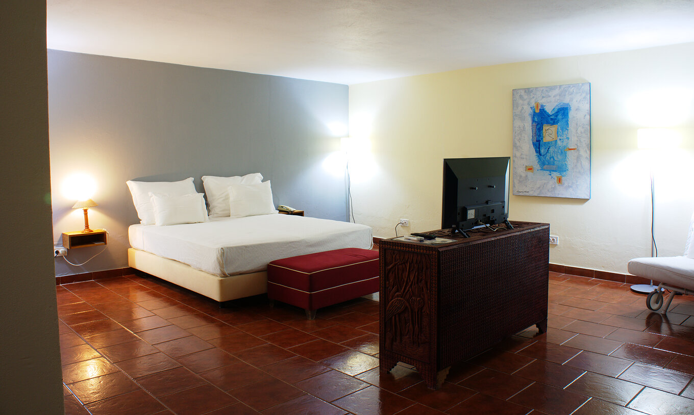 The Presidential Suite at Pestana Miramar São Tomé has a bedroom with a double bed and a  television facing the bed