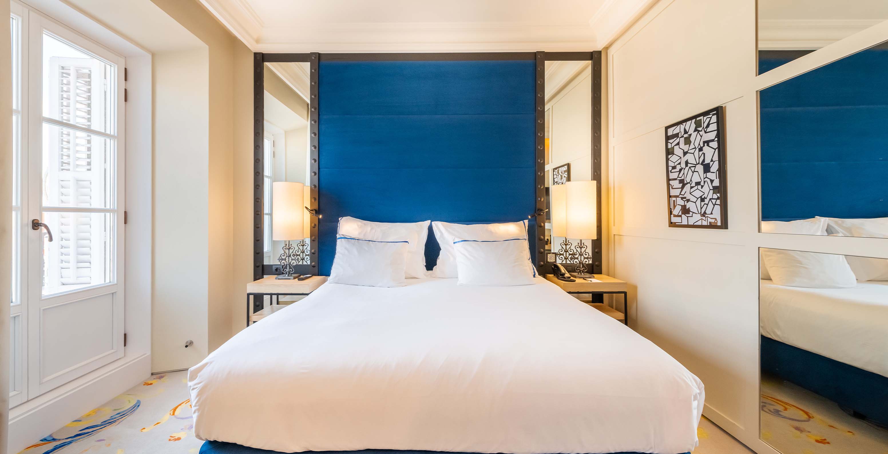 The Superior Plaza Mayor at Pestana Collection Plaza Mayor has a double bed with blue headboard with mirror and a large window