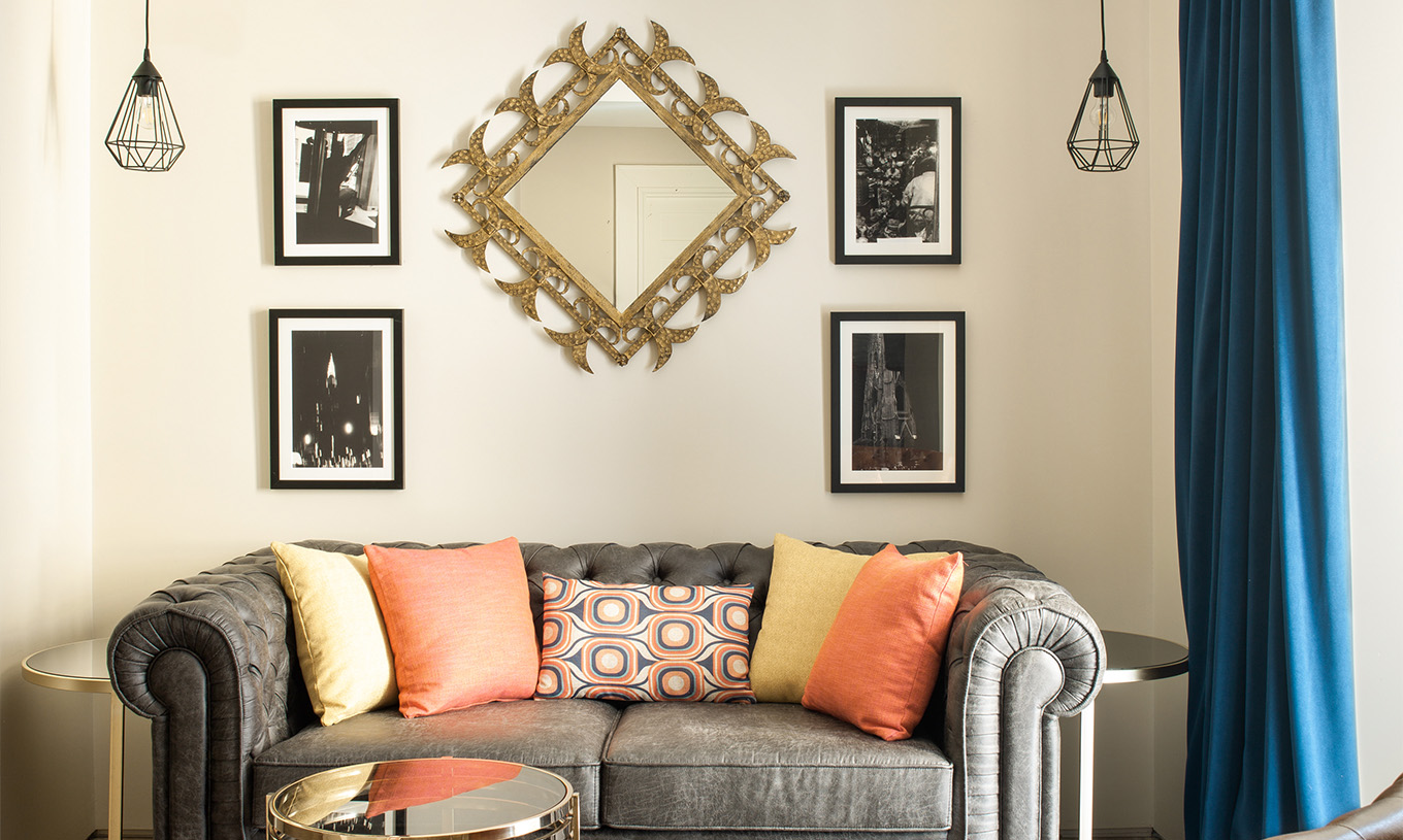 The Deluxe Grand Plaza Mayor at Pestana Plaza Mayor Madrid has a gray two-seater sofa and paintings on the wall