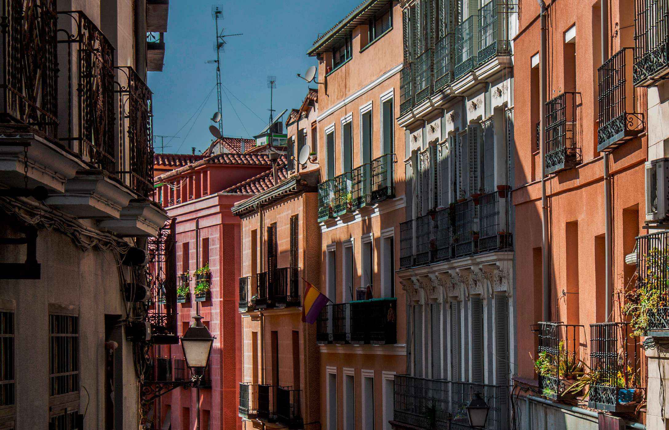 Street in the historic area of Madrid, Spain, with traditional colorful buildings, balconies, and plants