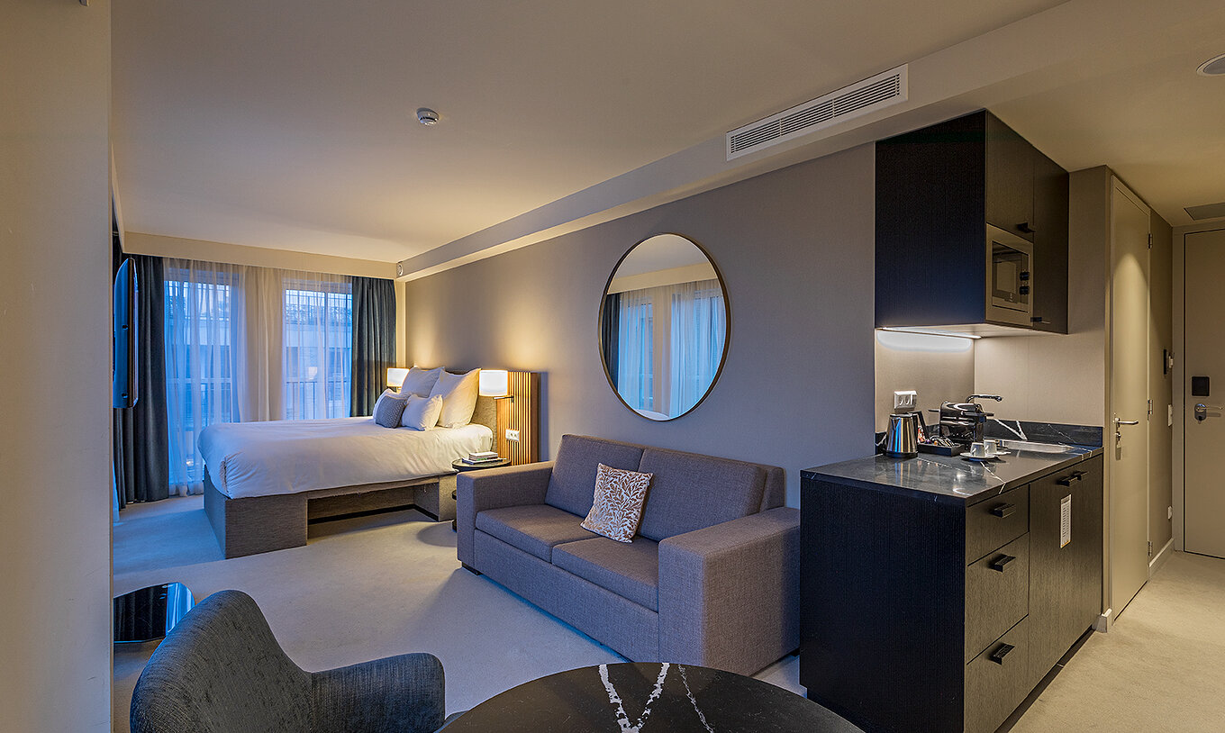 Comfort Studio room at Pestana Amsterdam Riverside has a double bed, with gray sofa and a mirror above