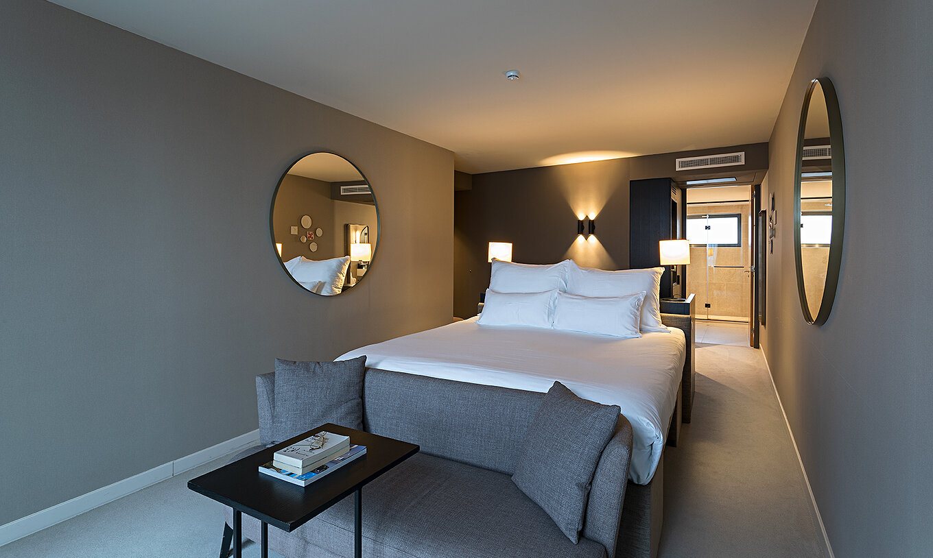 Executive - River View room at Pestana Amsterdam Riverside has a double bed, with a sofa in front and mirror