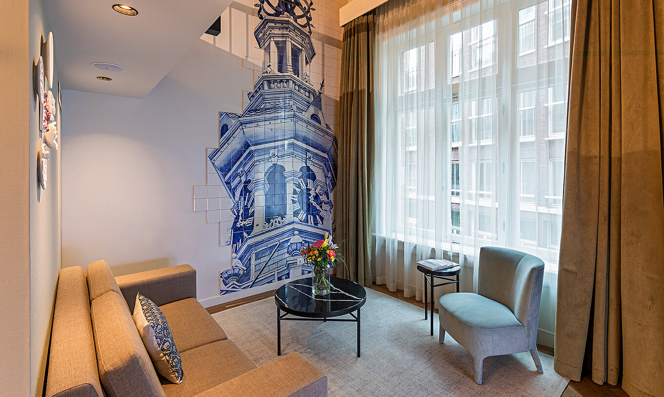 Mezzanine Suite at Pestana Amsterdam Riverside has a living room with sofa, coffee table with flowers, and tiles
