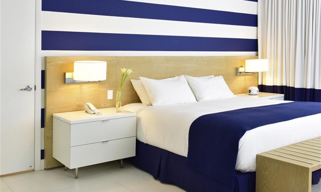 The Superior King at Pestana Miami South Beach has a double bed, bedside table and a lamp