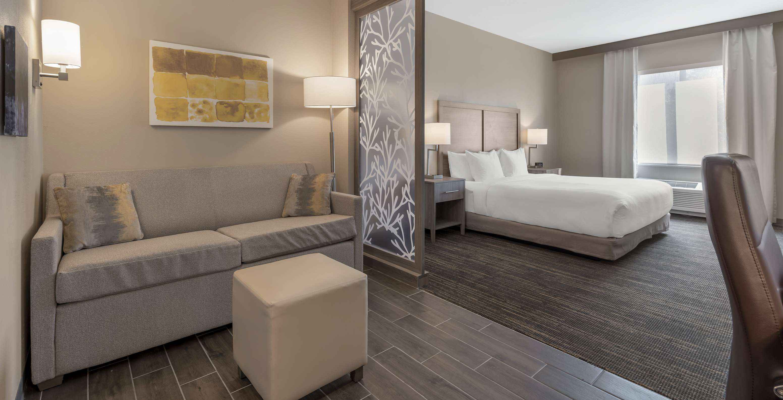 The King Suite at Pestana Orlando Suites Lake Buena Vista includes a double bed, a bedside table, a sofa, and a lamp