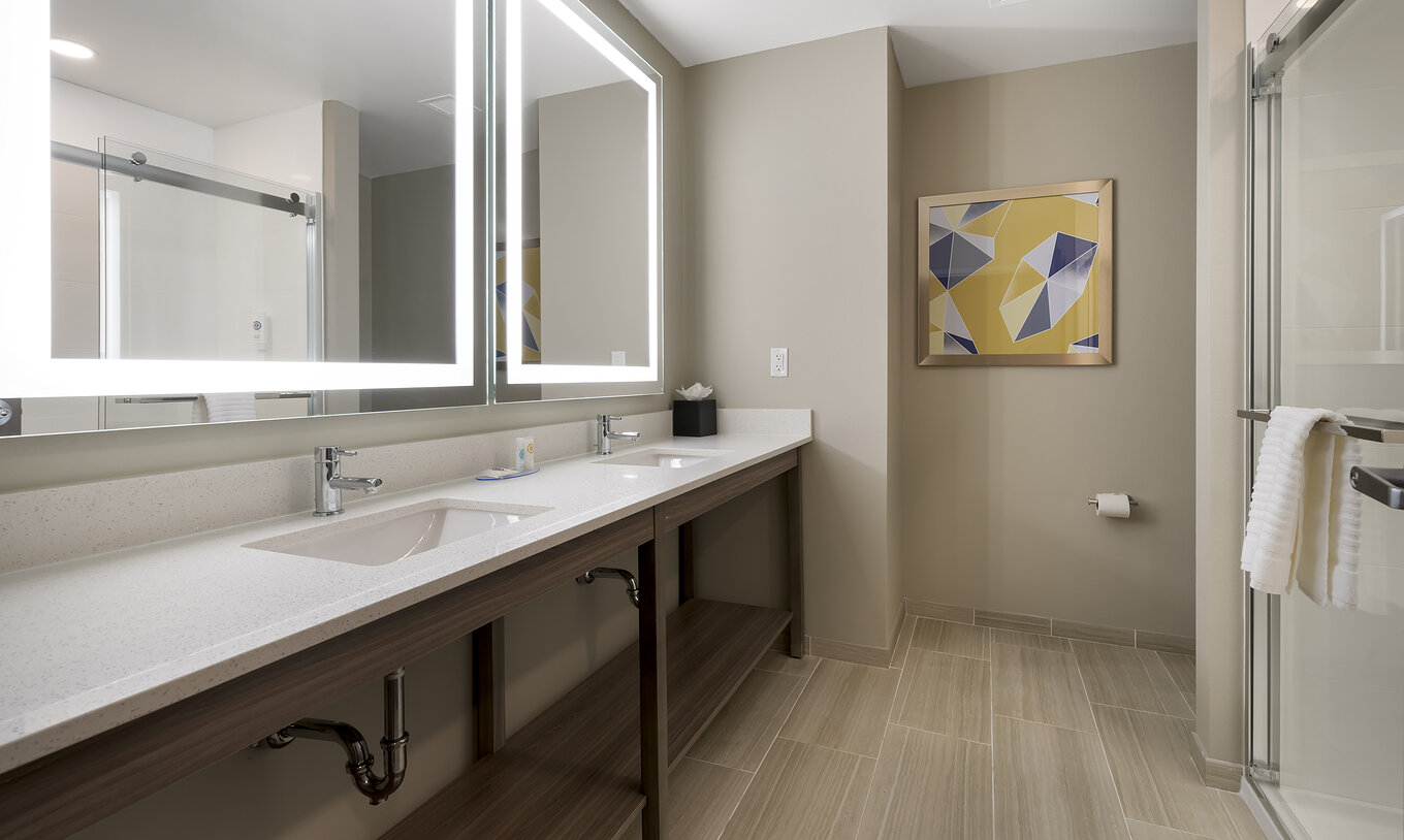 The Master Double Queen Suite at Pestana Orlando Suites Lake Buena Vista features a bathroom with two mirrors and a sink