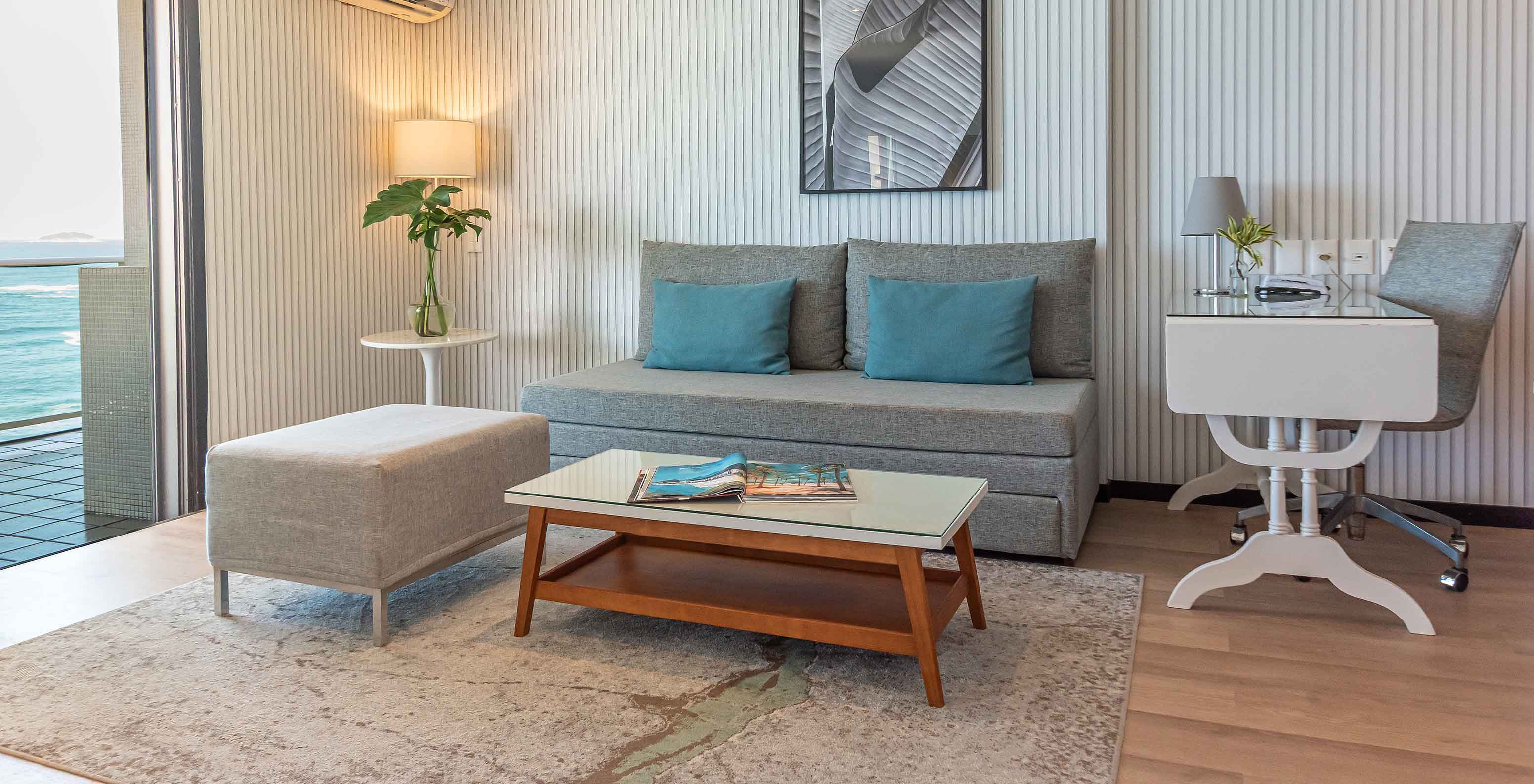 La Suite Frente al Mar del Pestana Rio Atlântica tiene sala moderna con sofá, escritorio y vista al mar.