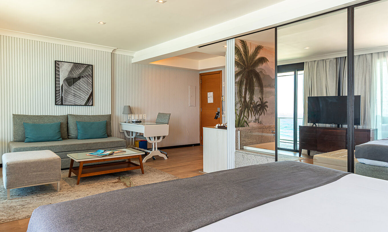 La Suite Frente al Mar del Pestana Rio Atlântica tiene cuarto moderno con cama, sofá, mesa y TV.