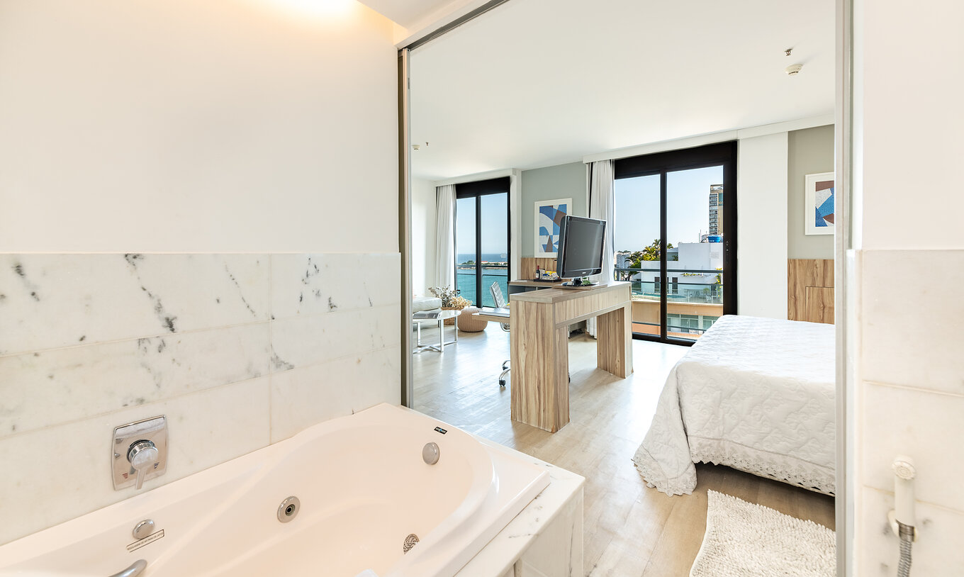 La Suite Junior con Vista Lateral al Mar del Pestana Rio Atlântica tiene un baño con bañera de inmersión y un cuarto con televisión