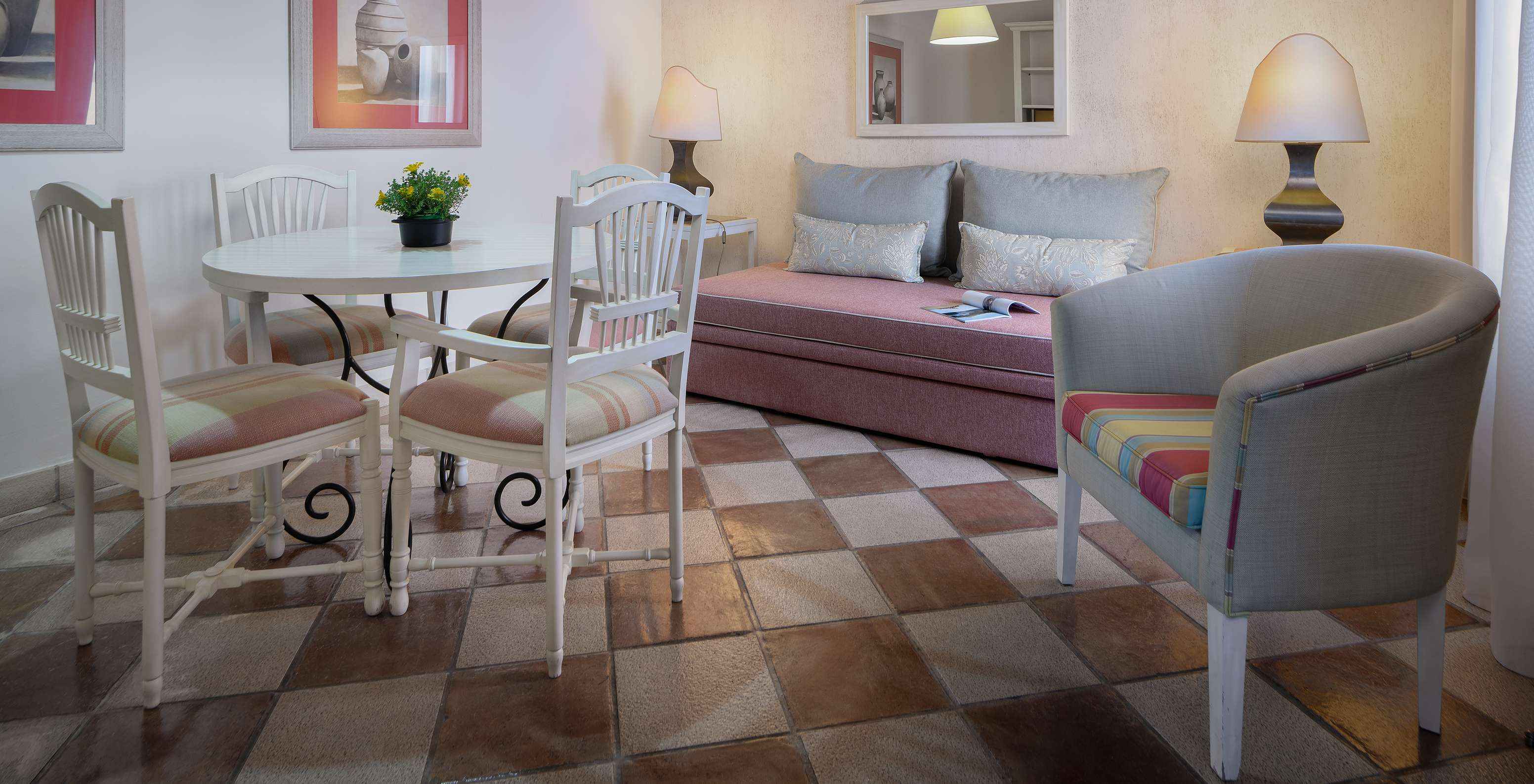 La Suite Vista Jardín del Pestana Vila Sol - Vilamoura tiene una sala con sofá, mesa, sillas y un espejo en la pared