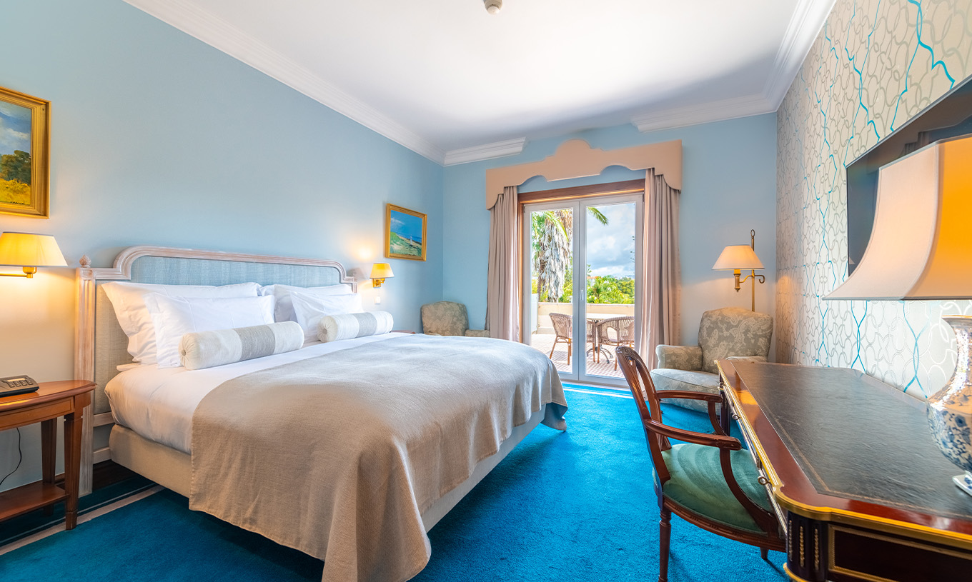 El Premium Balcony del Pestana Palace Lisboa tiene una cama, paredes pintadas de azul claro y una ventana con cortinas