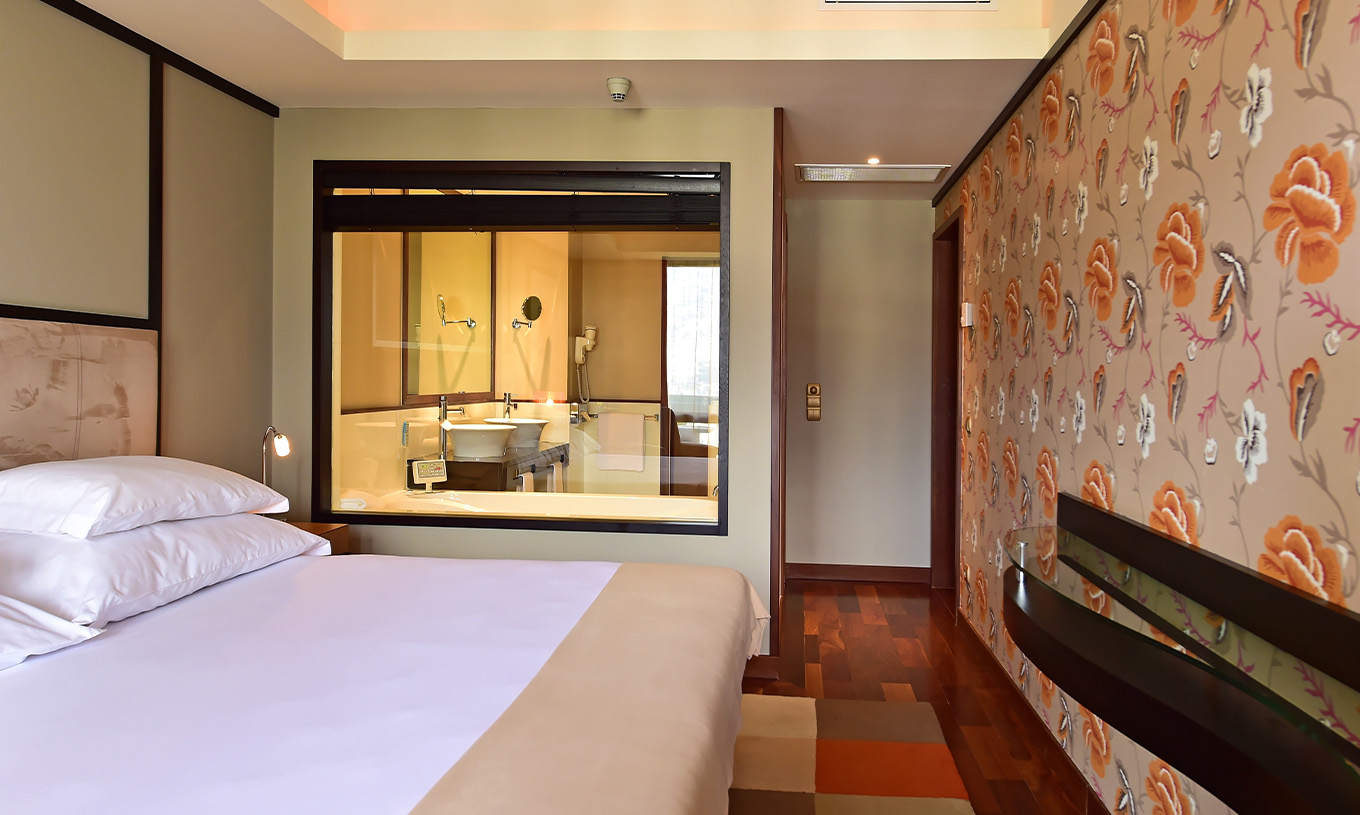 La Suite Presidencial del Pestana Casino Park tiene cama de matrimonio con vidrio hacia el baño y papel pintado decorativo