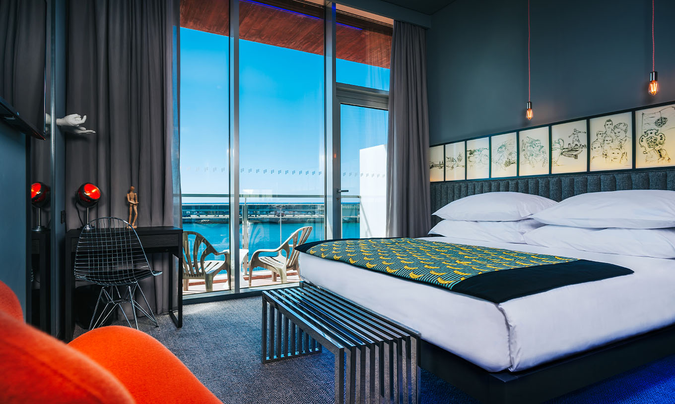 La Habitación CR Superior del Pestana CR7 Funchal tiene un balcón al lado de la cama doble, que tiene sillas y vista al mar