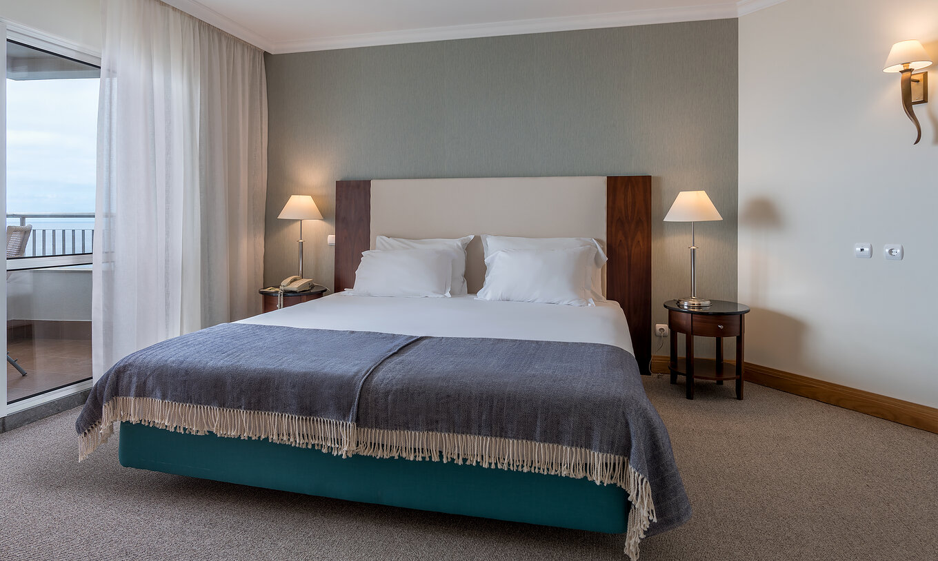 El cuarto Twin Superior Vista Mar del Pestana Grand tiene cama de matrimonio con mesita de noche y lámparas