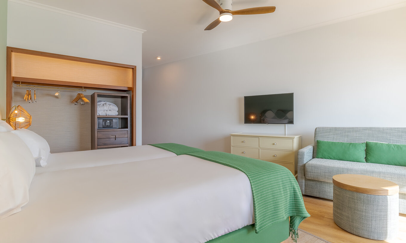 El Clásico Vista Mar del Pestana Vila Lido Madeira tiene una televisión en la pared, un armario con caja fuerte y dos camas