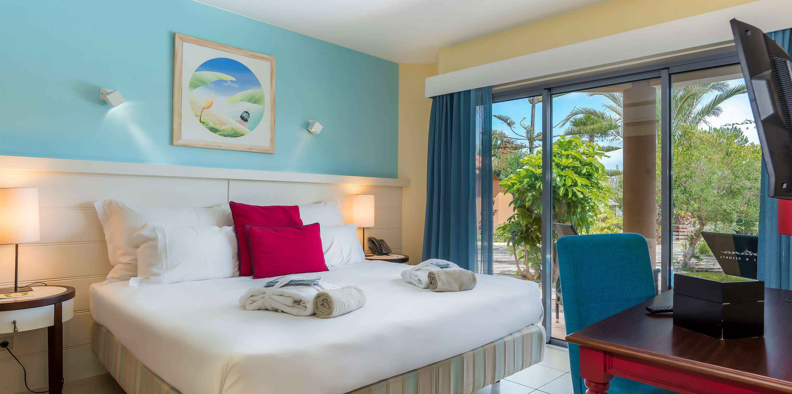 La Pool Villa del Pestana Porto Santo All Inclusive tiene un cuarto en tonos de azul, con cama de casal y una ventana grande