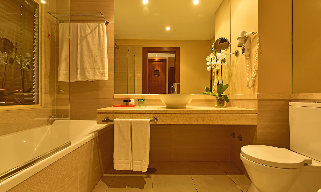 La Suite Apartamento T2 del Pestana Porto Santo All Inclusive tiene un baño con lavabo, toallas, espejo e inodoro