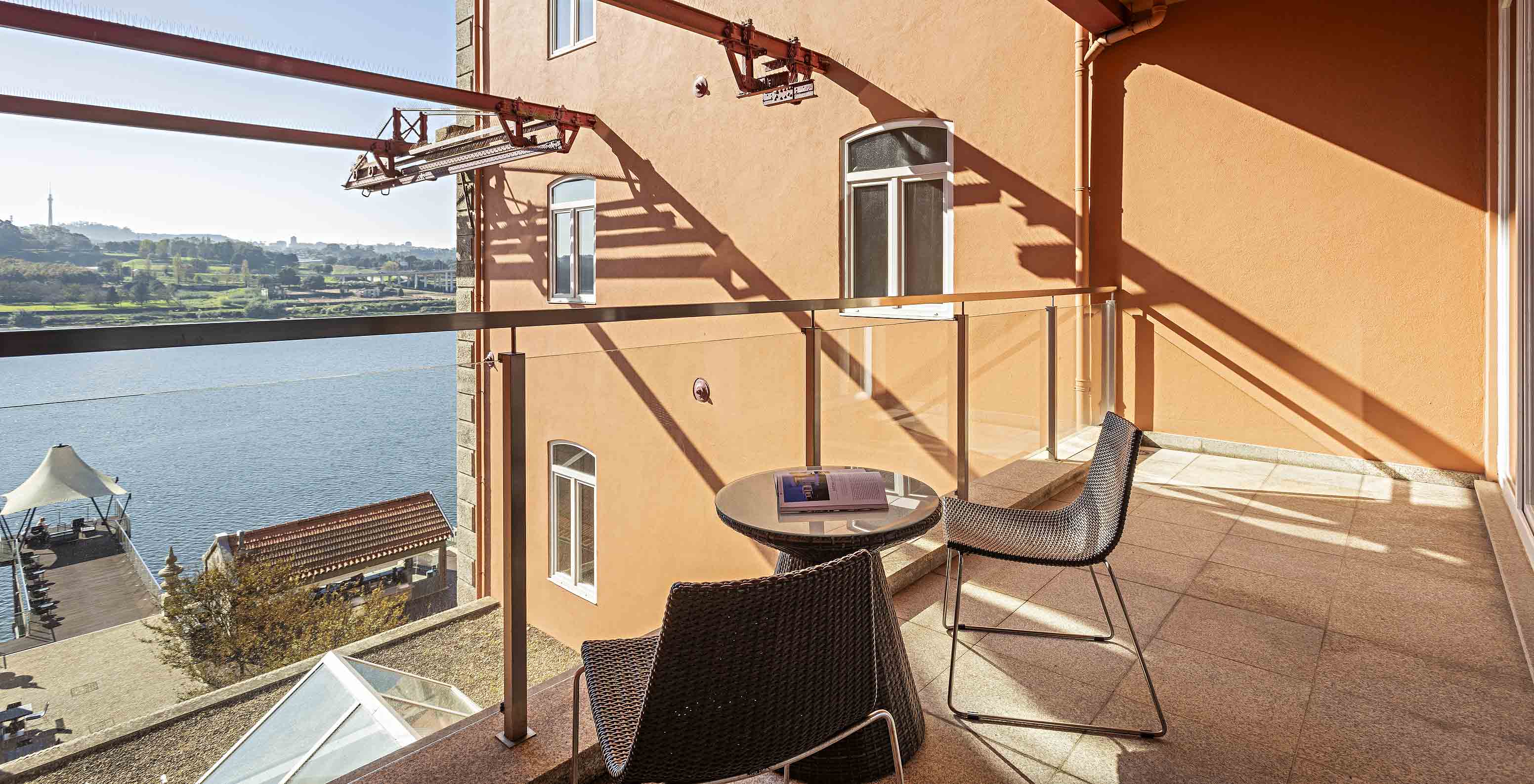 La Suite Balcony tiene un balcón con mesa, dos sillas y vista al río Duero