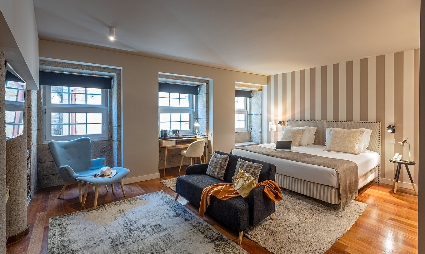 La Heritage Suite del Pestana Vintage Porto tiene una cama doble, dos sofás sobre alfombras y varias ventanas