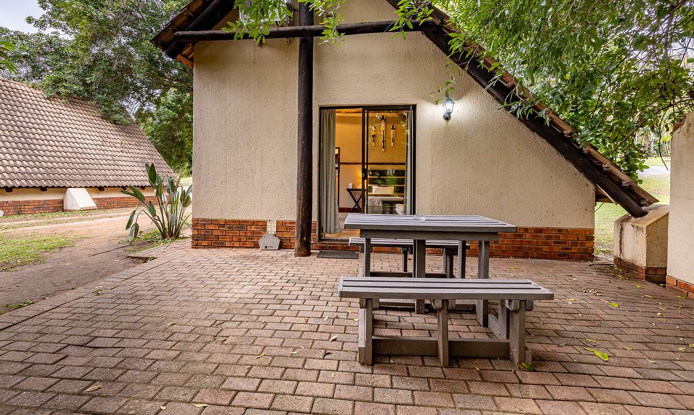 El Quarto Familiar del Pestana Kruger Lodge tiene una zona exterior con una mesa corrida de madera, con vista para o jardim